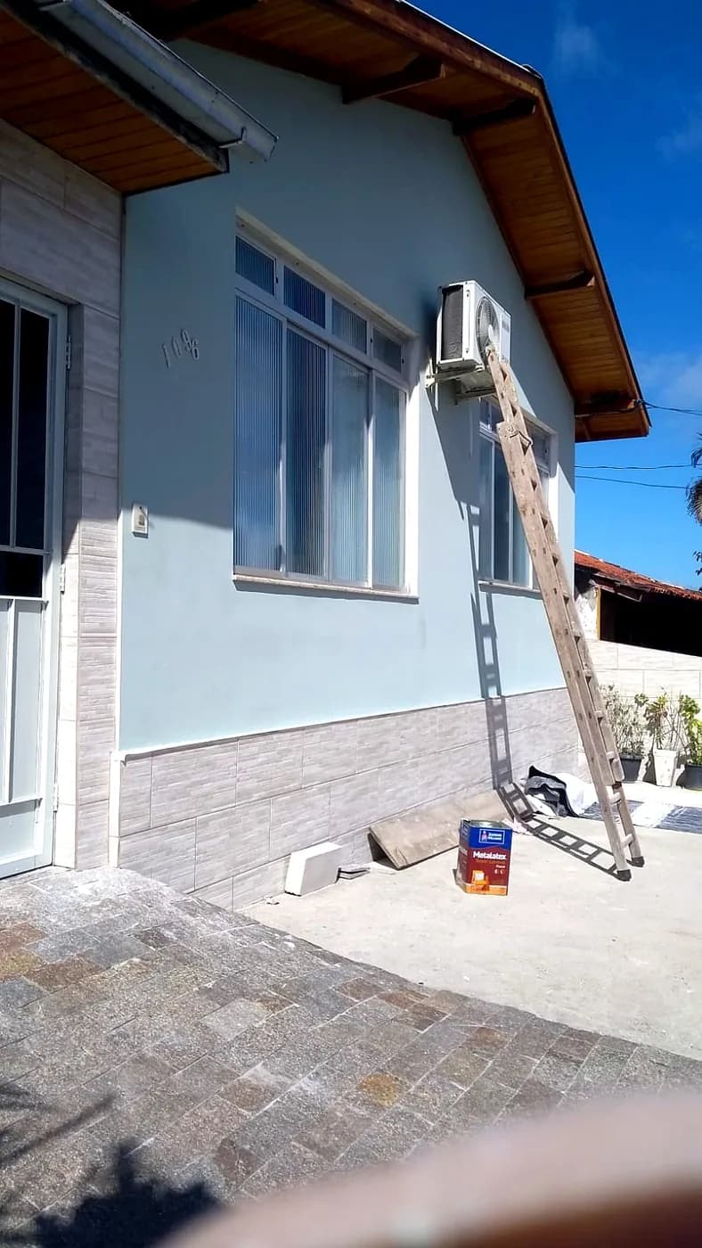Fachada de casa após pintura, acabamento azul claro com revestimento na base