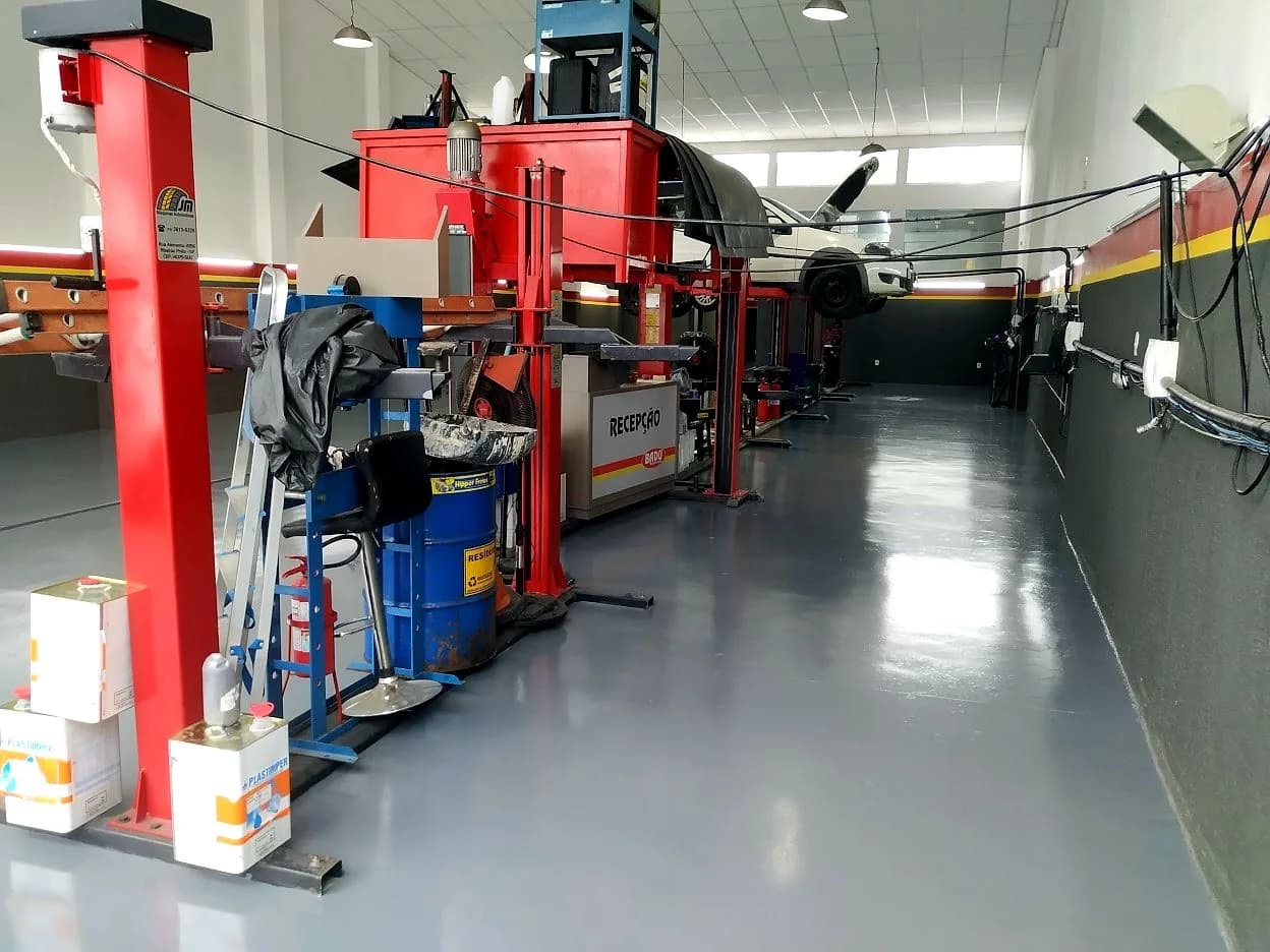 Piso epóxi cinza em oficina mecânica com elevadores automotivos